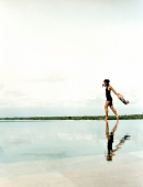 Woman running on water's edge with reflection. - Jack Hollingsworth