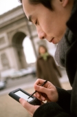 Profile of man using PDA, Arc de Triomphe  in background. - Leila  Pivetta