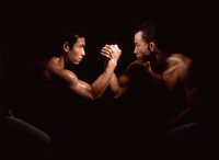 Two men arm wrestling, black background - Eric Ceret