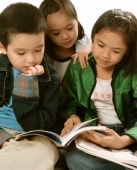 Three young children (two girls, one boy) reading books. - Jade Lee