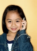 Young girl using cellular phone, portrait, yellow background. - Jade Lee