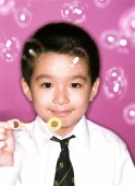 Young boy blowing bubbles, portrait, purple background. - Jade Lee