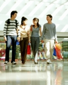 Two young men and two young women walking in shopping mall. - Jack Hollingsworth