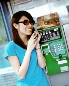 Young woman with sunglasses on public phone. - Jack Hollingsworth