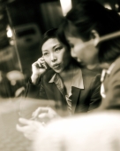 Female executives using PDA and cellular phone seen through glass window. - Jack Hollingsworth