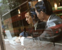 Male executives using laptop seen through glass window. - Jack Hollingsworth