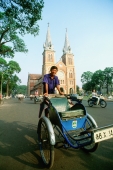 Vietnam, Saigon, Man on cyclo in front of Notre Dame Cathedral - Gareth Jones