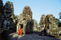 Cambodia, Angkor Thom, monks walking between face towers of the Bayon - Gareth Jones