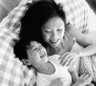 Mother and son playing in bed, laughing - Jade Lee