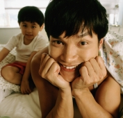 Man in bed, son in background, portrait - Jade Lee