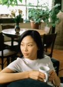 Woman sitting with a cup looking off camera - Jade Lee