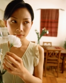 Woman holding flower at home - Jade Lee