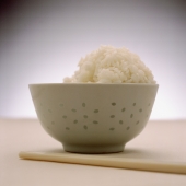 Half-eaten bowl of rice with chopsticks in foreground - Gareth Brown
