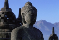 Indonesia, Java, Buddha figure at Borobudur temple, mountains in background - Jill Gocher