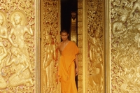Laos, Luang Prabang, A young monk stands in the doorway of a temple - Jill Gocher