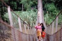 Malaysia, Sabah, Villagers walk across a hanging bridge. - Jill Gocher