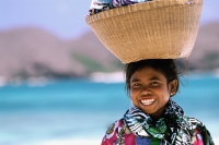 Indonesia, Lombok , Tanjung Aan, girl on beach, basket on head. - Jill Gocher