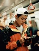 Young man on train using PDA. - Jack Hollingsworth