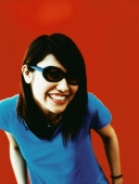 Young woman in sunglasses, smiling, red background. - Jack Hollingsworth