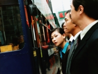 Executives waiting for bus, female executive looking at camera. - Jack Hollingsworth