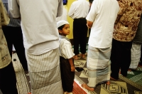 Singapore, boy wearing songkok prayer cap stands among men worshipping at the Hajjah Fatimah Mosque. - Steve Raymer