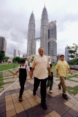 Malaysia, Kuala Lumpur, Malay family walking, Petronas Twin Towers in background. - Steve Raymer