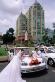 Vietnam, Ho Chi Minh City, A bride and groom leaning on decorated car. - Steve Raymer