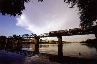 Thailand, Kanchanaburi, River Kwai, A train on the Siam-Burmese bridge crosses the River Kwai. - Steve Raymer