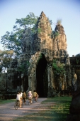 Cambodia, Siem Reap, Villagers on bicycles ride into the South Gate entrance to Angkor - John McDermott