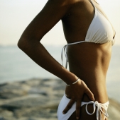 Upper torso of tanned woman wearing white bikini at beach - Erik Soh