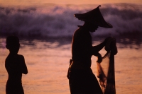Indonesia, Java, Fisherman sorting nets by the beach accompanied by a boy. - Jill Gocher
