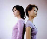 Two young women standing back to back, white background. - Eric Ceret