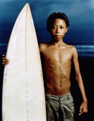 Indonesia, Bali, Kuta Beach, Young surfer holding surfboard on the beach. - Martin Westlake