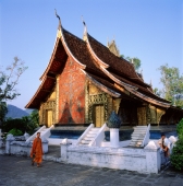 Laos, Luang Prabang, Novice monk walks in front of Wat Xieng Thong Temple. (grainy) - Martin Westlake