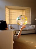 Man sitting, holding plastic globe with one hand, back view. - Carsten Schael