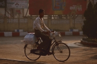 Myanmar (Burma), Pyay, Young man in longyi riding bicycle. - Martin Westlake