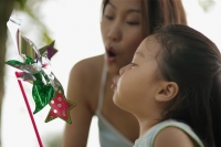 Young girl and mother blowing a pinwheel - Alex Microstock02