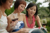 Young women browsing through magazine, wine glasses in hand - Alex Microstock02