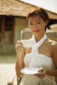 Young woman holding cup and saucer, looking at camera - Alex Microstock02
