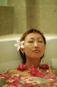Woman relaxing in tub, flowers floating around her - Alex Microstock02