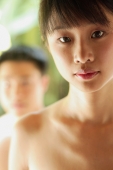 Young woman looking at camera, man in the background - Alex Microstock02