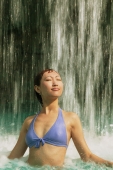 Young woman in swimming pool, water cascading on her, eyes closed - Alex Microstock02