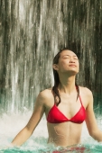 Young woman in swimming pool, water cascading on her, eyes closed - Alex Microstock02