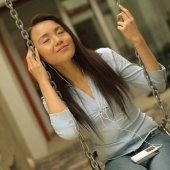 Young woman on swing, listening to personal stereo - Eckersley/Peacock