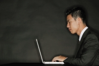 Young man using laptop, side view - Alex Microstock02