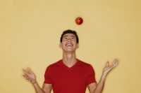 Young man juggling a ball, yellow background - Alex Microstock02