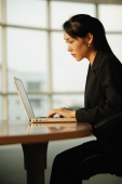 Young woman sitting at desk, using laptop - Alex Microstock02