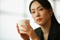 Young woman sitting at desk, holding mug - Alex Microstock02