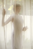Young woman standing behind curtain - Jack Hollingsworth