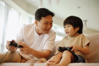 Father and son sitting on sofa, playing with video game - Alex Microstock02